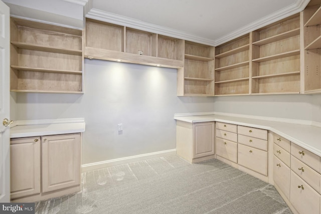 kitchen with light brown cabinetry, light colored carpet, and ornamental molding