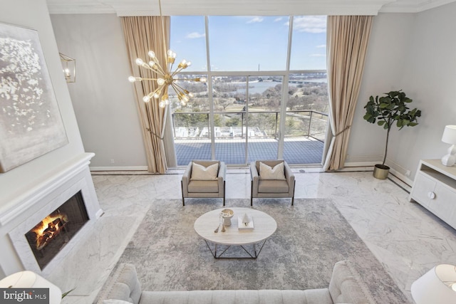 living area with a chandelier, plenty of natural light, ornamental molding, and a high end fireplace