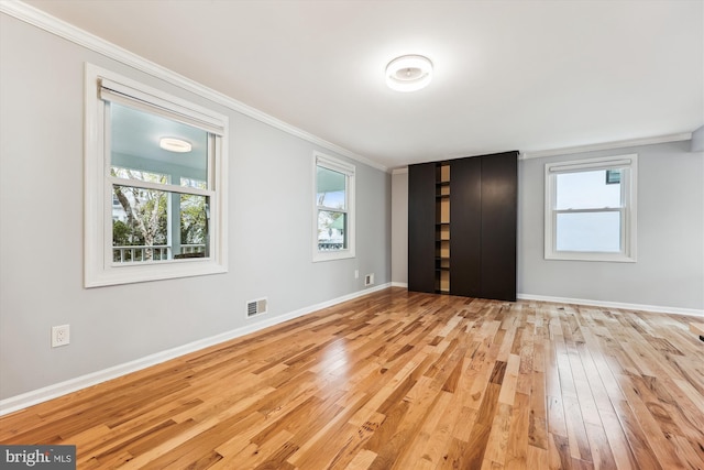 interior space with a healthy amount of sunlight, light hardwood / wood-style floors, and crown molding