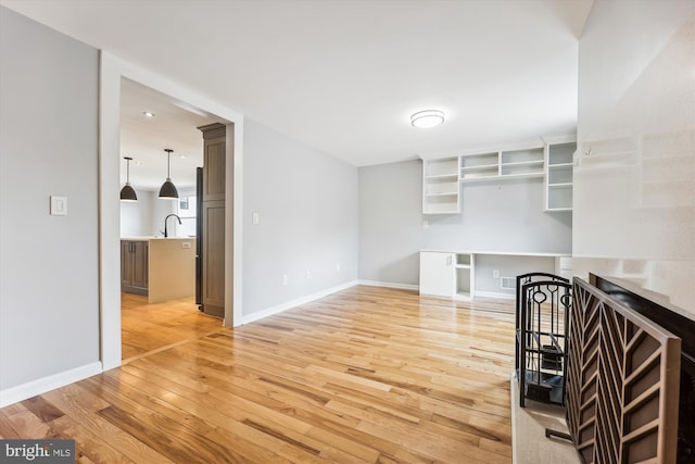 kitchen with pendant lighting, light hardwood / wood-style floors, and sink