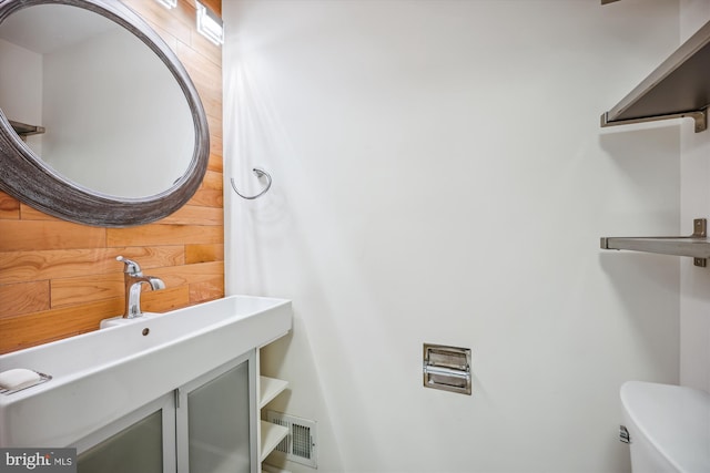 bathroom featuring vanity, toilet, and wooden walls