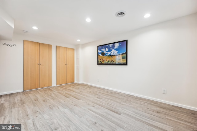 unfurnished bedroom with light wood-type flooring and multiple closets