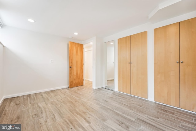 unfurnished bedroom with multiple closets and light hardwood / wood-style flooring