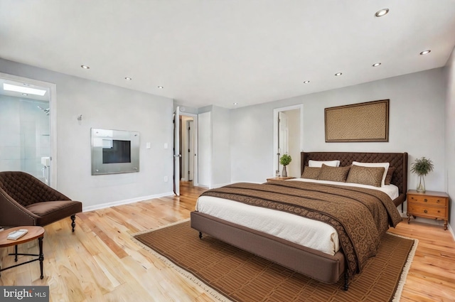 bedroom with connected bathroom and light hardwood / wood-style floors