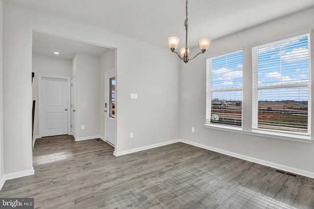 empty room featuring hardwood / wood-style flooring and a notable chandelier