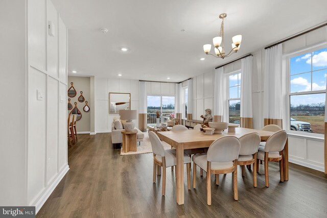 dining area with dark hardwood / wood-style flooring, a wealth of natural light, and a chandelier