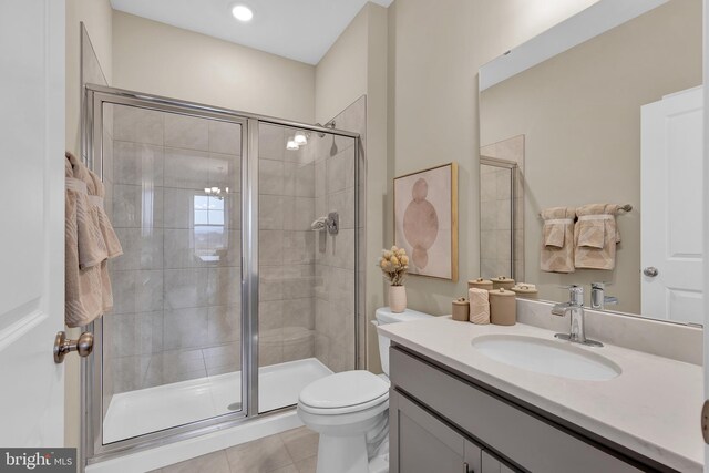 bathroom with tile patterned flooring, vanity, toilet, and walk in shower