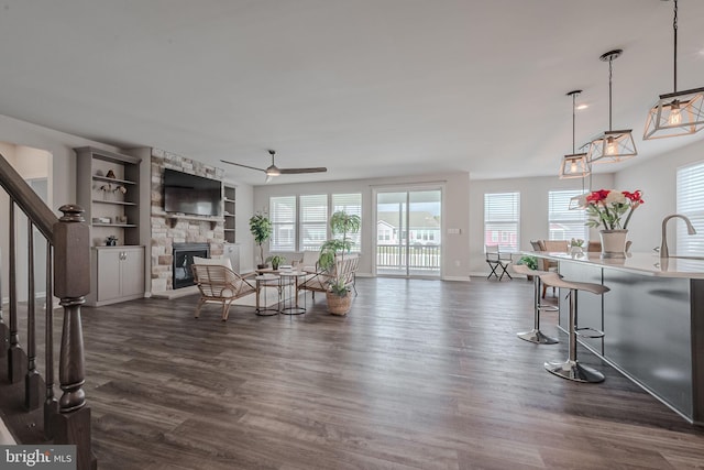 living room with sink, dark hardwood / wood-style floors, ceiling fan, built in shelves, and a fireplace