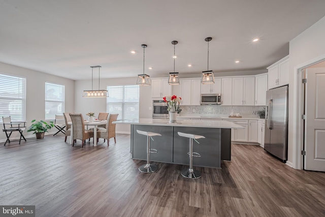 kitchen with white cabinets, plenty of natural light, wood-type flooring, and appliances with stainless steel finishes