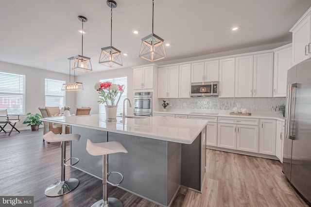 kitchen with a wealth of natural light, white cabinets, stainless steel appliances, and decorative light fixtures