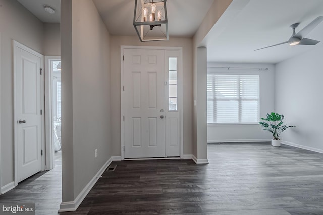 entrance foyer with ceiling fan with notable chandelier and dark wood-type flooring