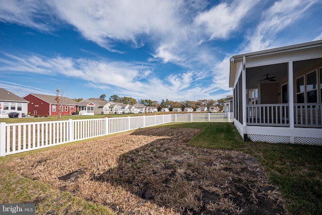 view of yard featuring a sunroom and ceiling fan