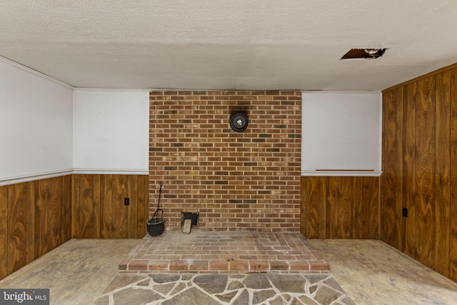 basement featuring wood walls and a textured ceiling