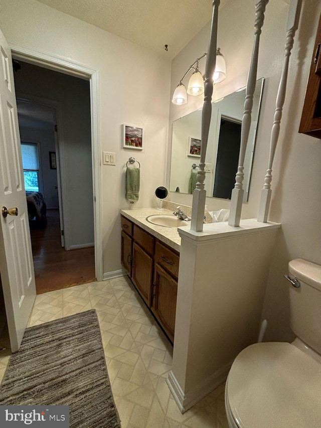 bathroom featuring wood-type flooring, vanity, a textured ceiling, and toilet