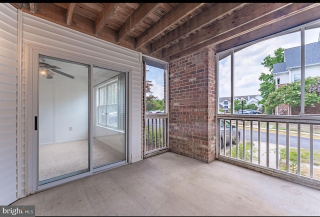 unfurnished sunroom featuring ceiling fan, beam ceiling, and wood ceiling