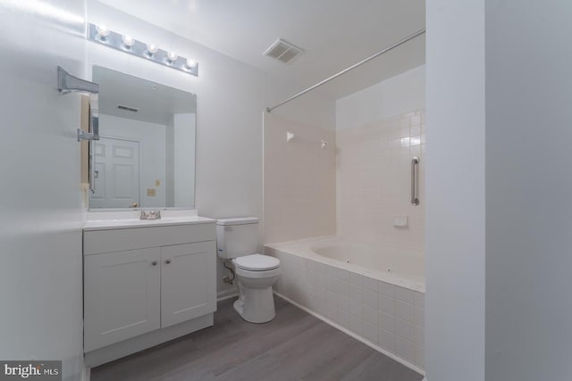 full bathroom featuring toilet, vanity, wood-type flooring, and tiled shower / bath