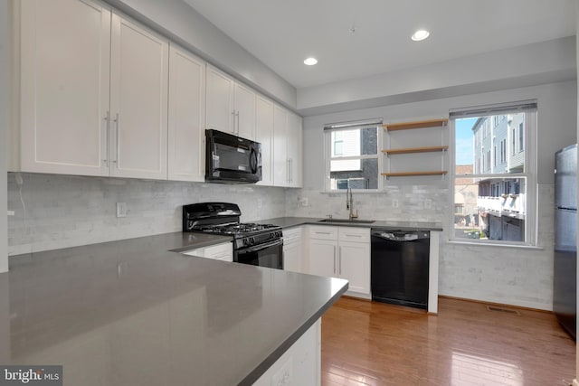 kitchen featuring tasteful backsplash, sink, black appliances, light hardwood / wood-style flooring, and white cabinets