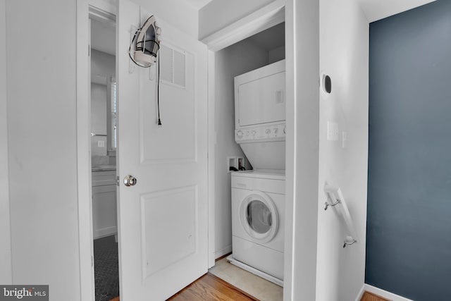 laundry area featuring light hardwood / wood-style floors and stacked washer / drying machine