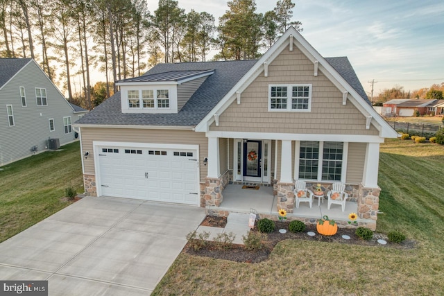 craftsman-style home featuring a lawn, central AC, a porch, and a garage