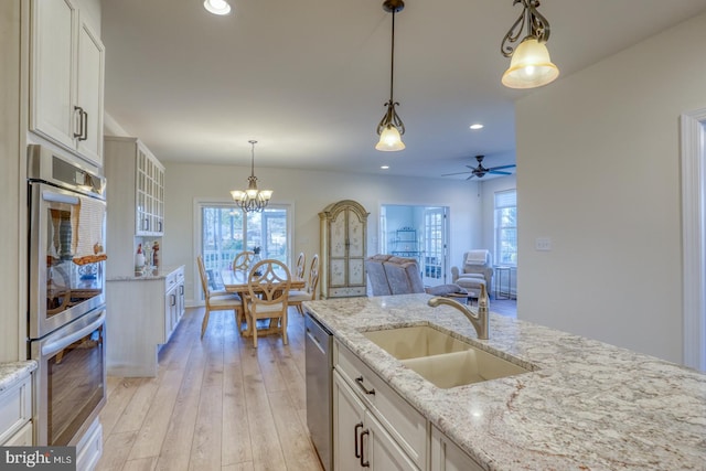 kitchen with sink, stainless steel appliances, light hardwood / wood-style floors, decorative light fixtures, and white cabinets