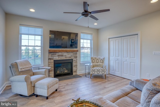 living room featuring ceiling fan, light hardwood / wood-style floors, and a fireplace