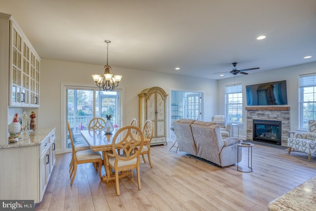 102 Serenity Cir, Middletown, DE 19709 - dining area featuring light wood-type flooring, a stone fireplace, a chandelier, recessed lighting, and ceiling fan