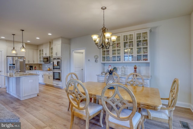 dining area with light hardwood / wood-style flooring and an inviting chandelier