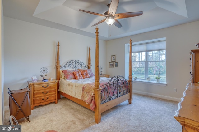 carpeted bedroom featuring ceiling fan and a raised ceiling