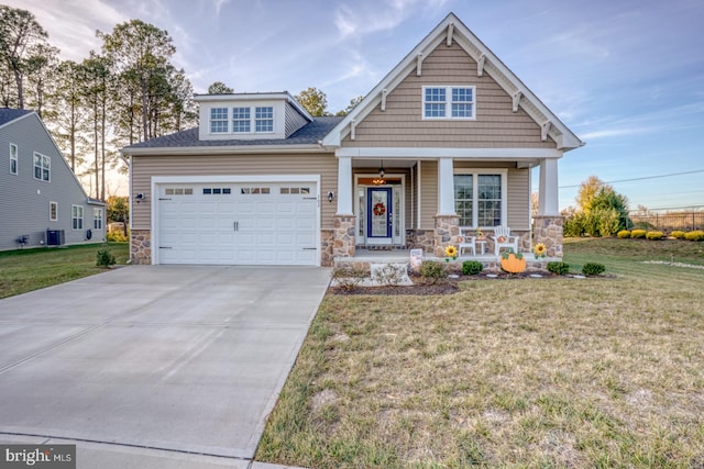 craftsman inspired home featuring cooling unit, covered porch, a front yard, and a garage