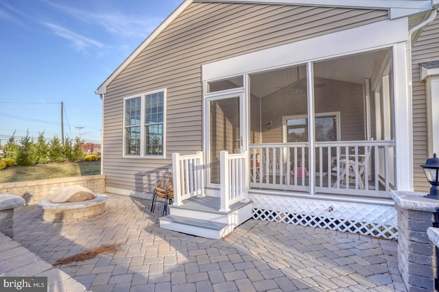 exterior space with a sunroom, a patio, and a fire pit