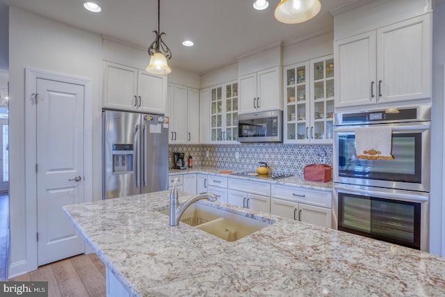 kitchen featuring white cabinets, decorative light fixtures, sink, and appliances with stainless steel finishes