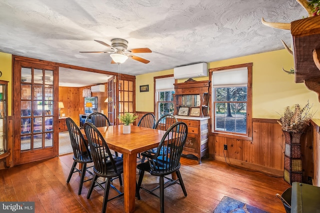 dining space with wood-type flooring, an AC wall unit, and wooden walls