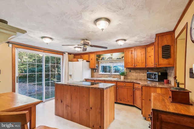 kitchen featuring a center island, sink, tasteful backsplash, white refrigerator with ice dispenser, and black electric cooktop