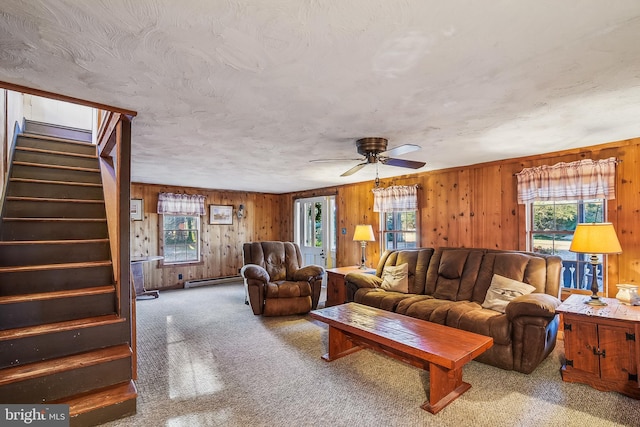 living room featuring ceiling fan, carpet floors, a healthy amount of sunlight, and wood walls