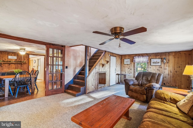 living room with carpet flooring, baseboard heating, ceiling fan, and wooden walls