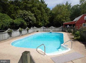 view of pool with a diving board and a patio