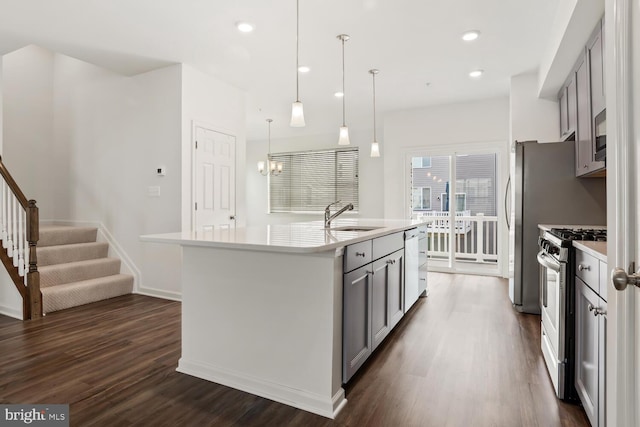 kitchen with a kitchen island with sink, hanging light fixtures, dark hardwood / wood-style floors, and appliances with stainless steel finishes