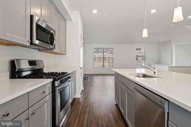 kitchen with appliances with stainless steel finishes, gray cabinetry, sink, pendant lighting, and dark hardwood / wood-style floors