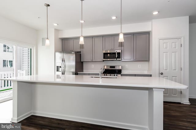 kitchen with dark wood-type flooring, appliances with stainless steel finishes, gray cabinets, and a large island