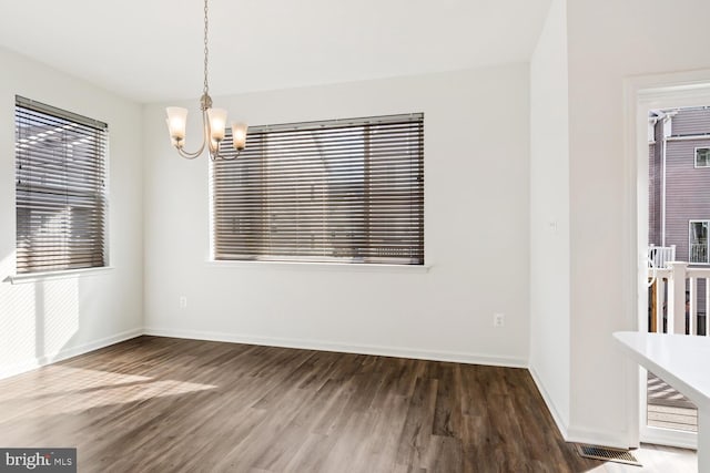 spare room featuring a chandelier and dark wood-type flooring