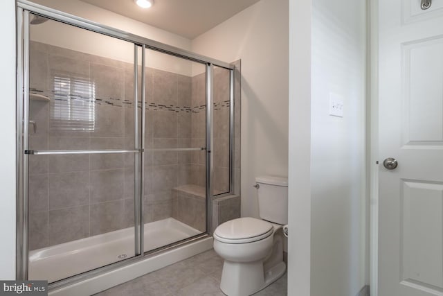 bathroom with tile patterned flooring, toilet, and a shower with shower door