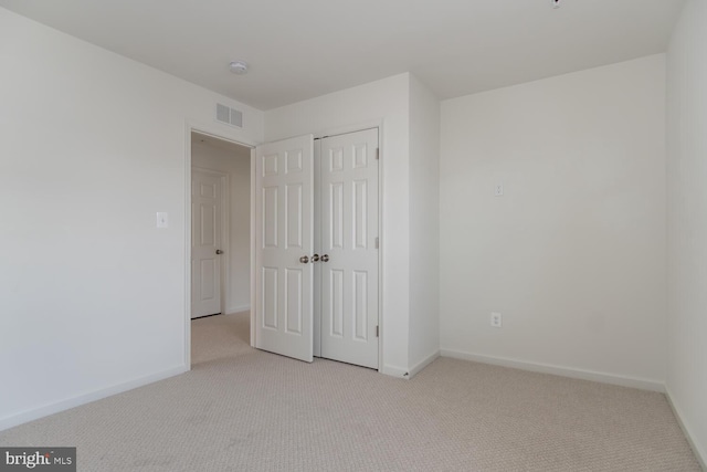 unfurnished bedroom with light carpet and a closet