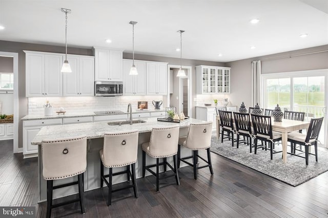 kitchen featuring a kitchen island with sink, white cabinets, dark hardwood / wood-style floors, and decorative light fixtures