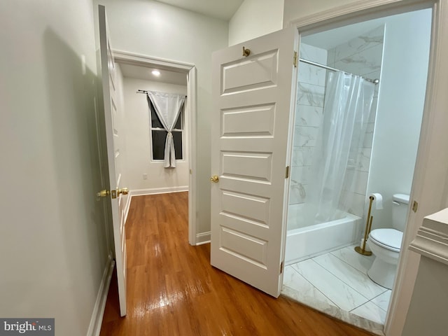 bathroom featuring shower / tub combo, hardwood / wood-style flooring, and toilet