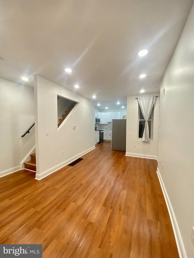 basement featuring stainless steel fridge and light hardwood / wood-style floors