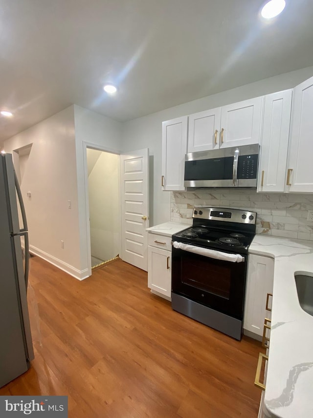 kitchen with decorative backsplash, white cabinetry, appliances with stainless steel finishes, and light hardwood / wood-style flooring