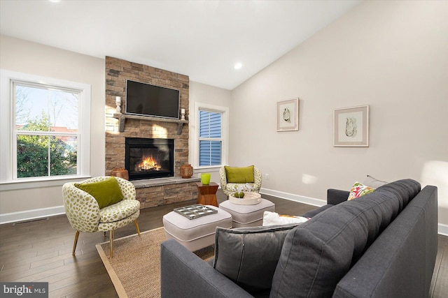 living room with dark hardwood / wood-style floors, vaulted ceiling, and a stone fireplace