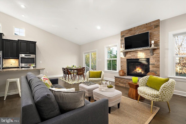 living room with dark hardwood / wood-style floors, a healthy amount of sunlight, lofted ceiling, and a fireplace