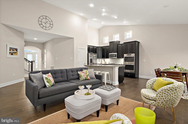 living room with dark hardwood / wood-style floors, high vaulted ceiling, and sink