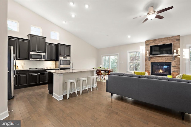 living room with ceiling fan, dark hardwood / wood-style flooring, a fireplace, and high vaulted ceiling